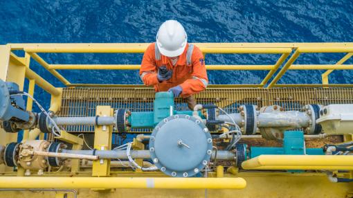 Offshore oil rig worker checking parameter of coriolis digital flow transmitter meter, instrument and electrical service of oil and gas energy business
