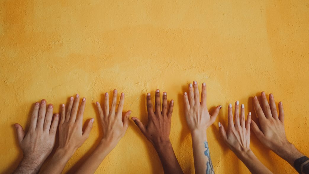 Diverse hands against a yellow wall