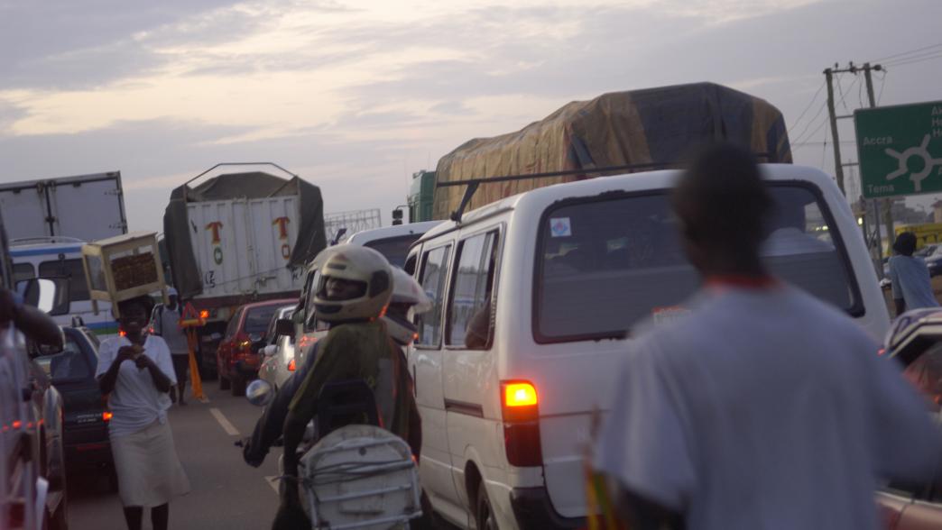Traffic in Ghana with vendors working between vehicles