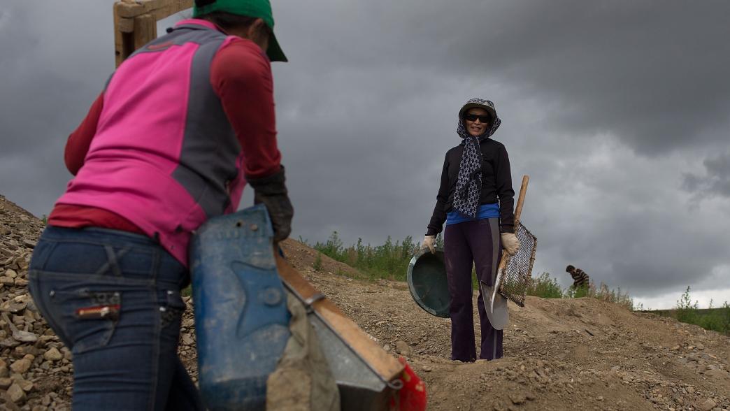 Female miners carry equipment up a hillside, Mongolia