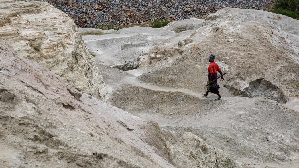 A woman walks on top of a hill formed from the old mining activities' residue