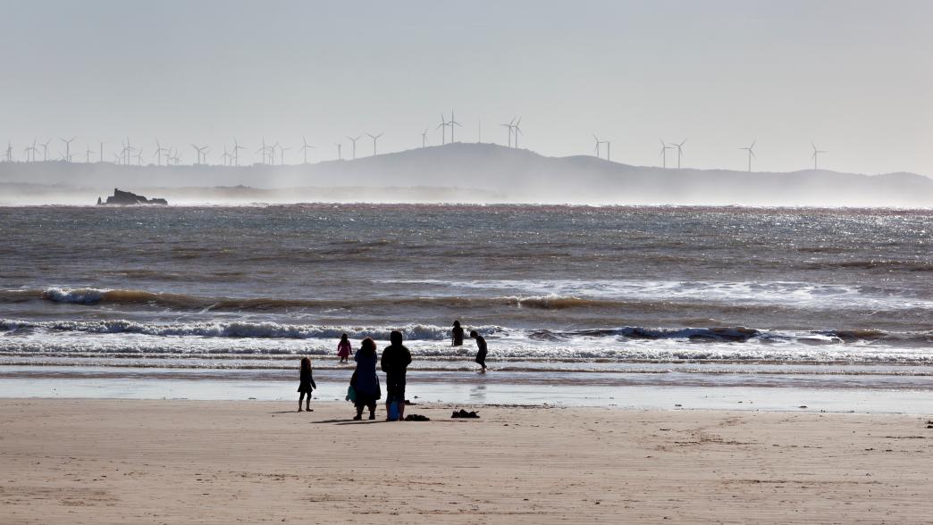 People beach in Morocco with wind turbines in the background