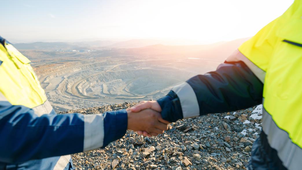 Two people shaking hands in front of a mine