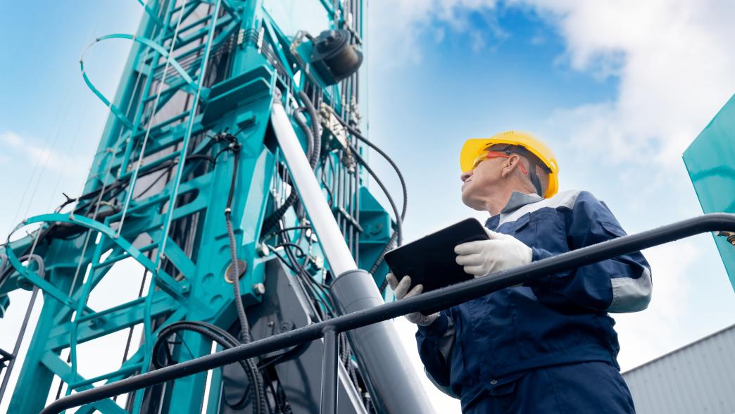 Man holding tablet and using it tol control a drilling rig
