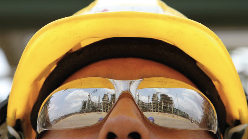 A close-up of a man's face wearing sunglasses and a yellow hard hat