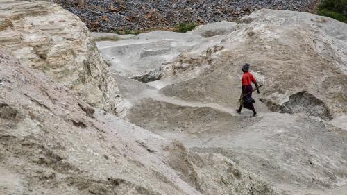 A woman walks on top of a hill formed from the old mining activities' residue