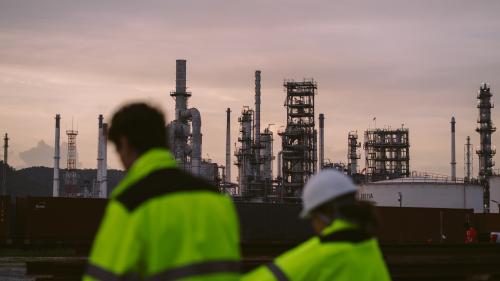 Two industrial workers, wearing high-visibility jackets, focus on background of refinery factory, Power plant infrastructure, chemical industry, energy sector. Night shift