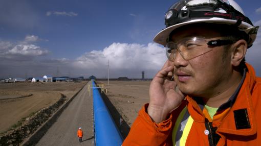 A Mongolian worker oversees operations along a blue conveyor belt at the Oyu Tolgoi mine in Mongolia's south Gobi desert
