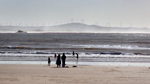 Wind turbines behind people on a beach in Morocco