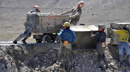 Coal mine workers pushing a cart in Bolivia
