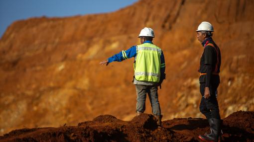Two workers dressed in safety uniforms oversee mining operations