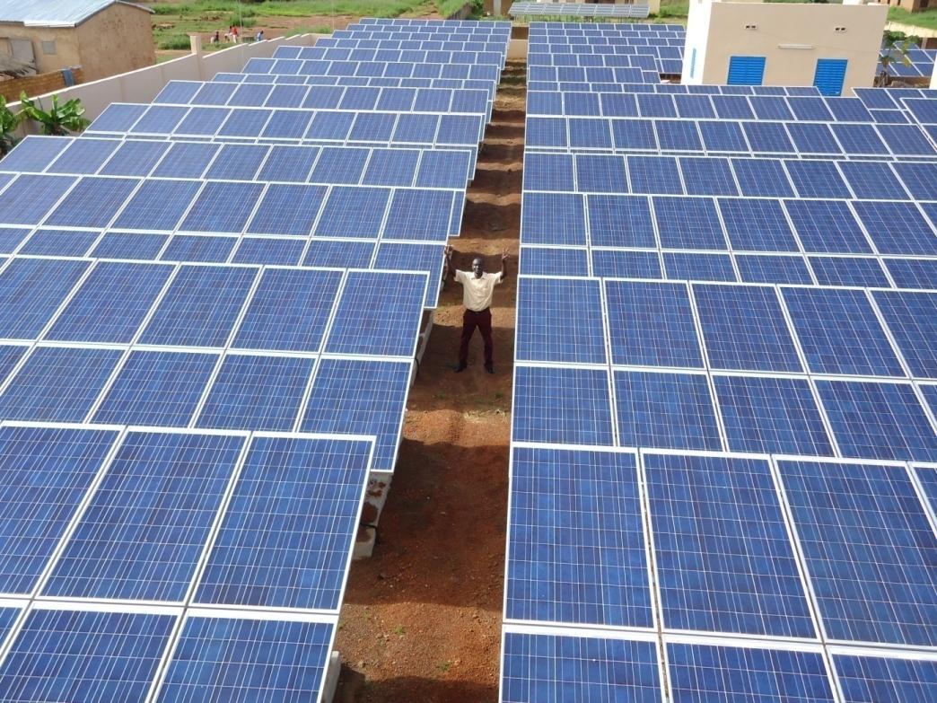 Man standing between solar panels in Mali